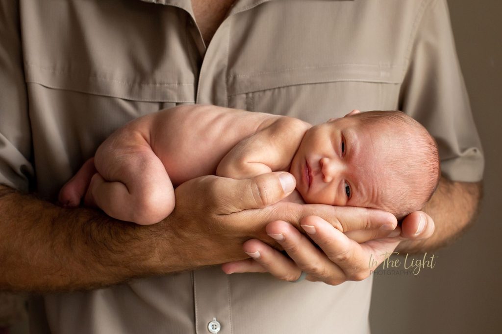 Newborn baby girl in her dad's big hands during her photo session in Centurion.
