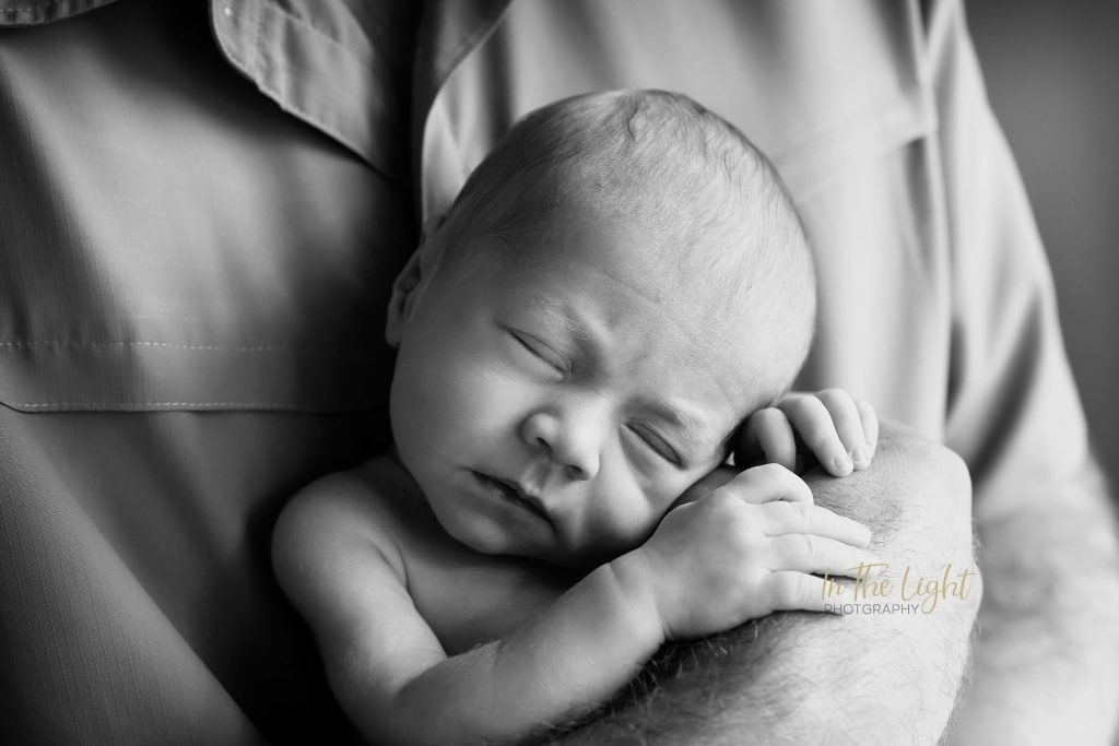 Newborn baby girl in her dad's big hands during her photo session in Centurion.