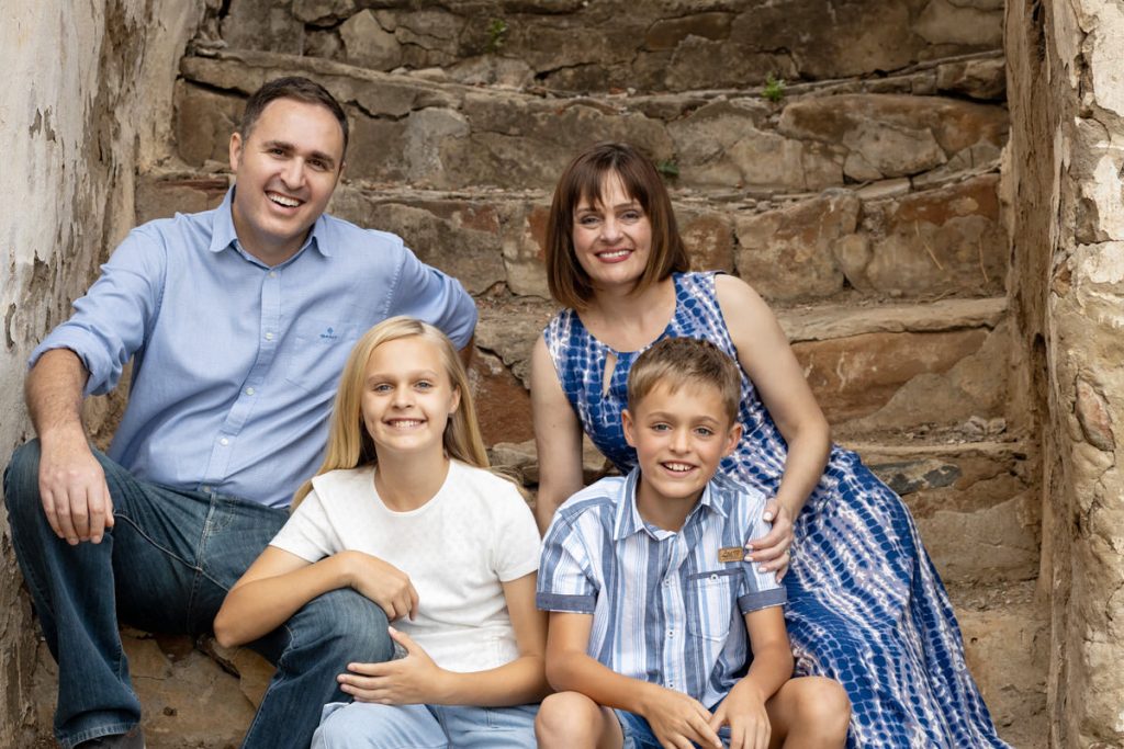 Family of four smiling posing for a photo on old steps in Hazeldean, Pretoria